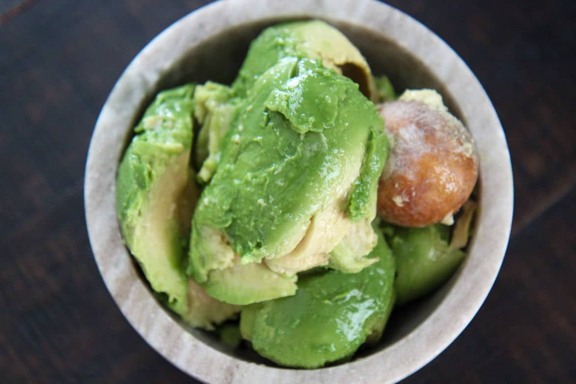 avocados and an avocado pit in a small bowl