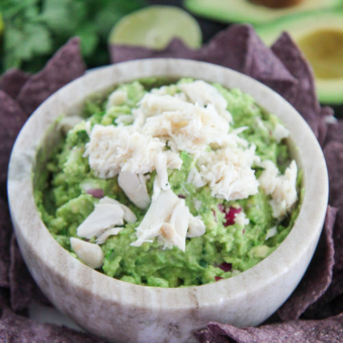 crab guacamole in a bowl with chips on the side