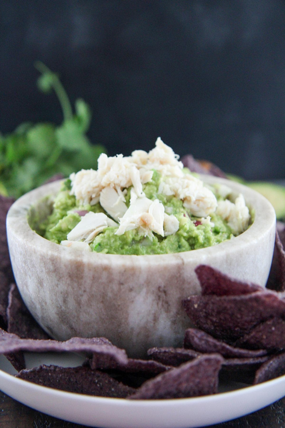 crab guacamole in a gray small bowl with purple chips on the side 