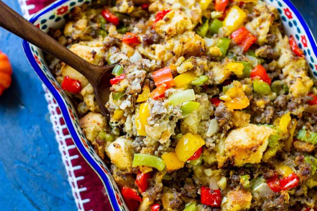 sausage stuffing in a casserole with a wooden spoon