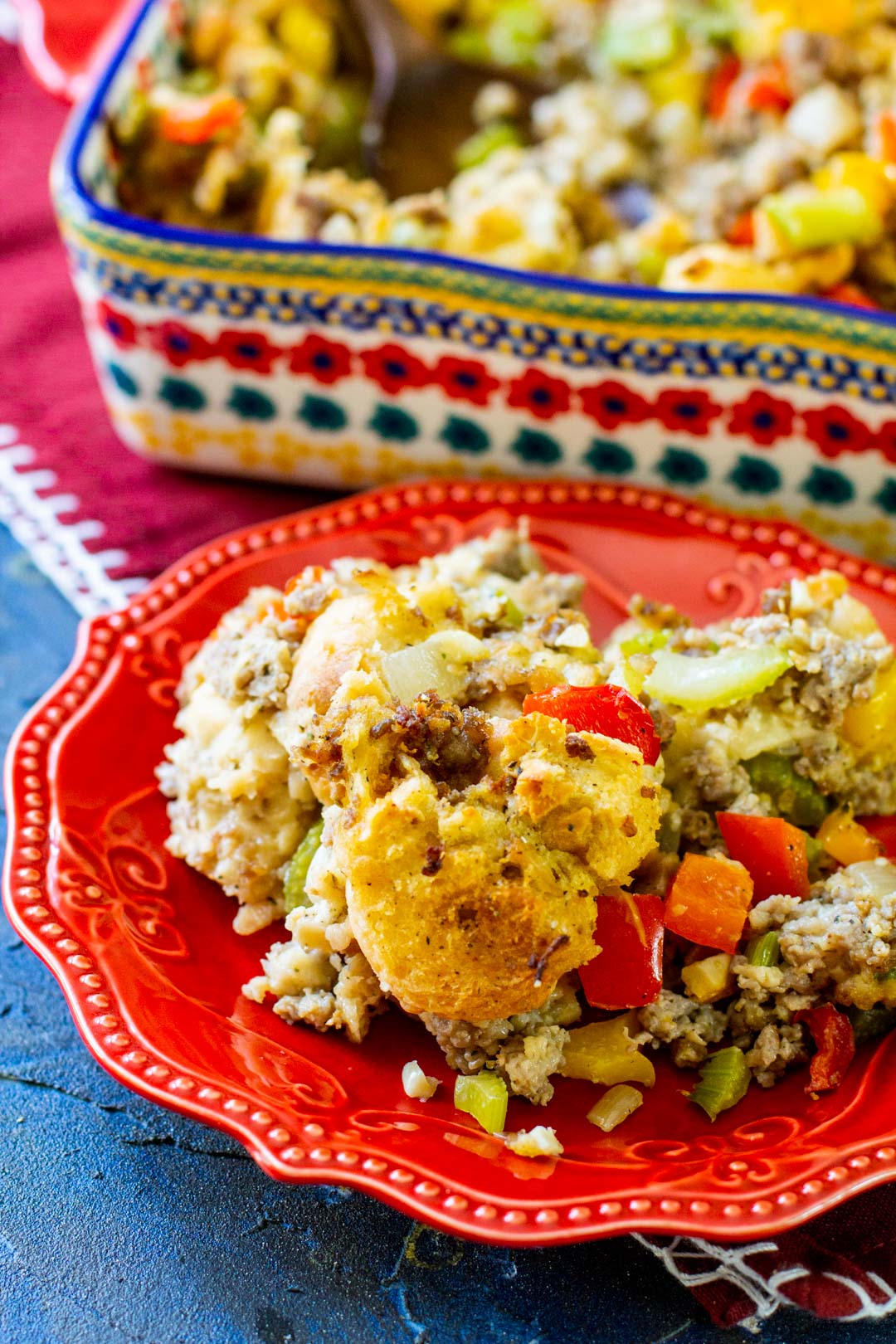 stuffing on a red plate with a casserole dish in the background