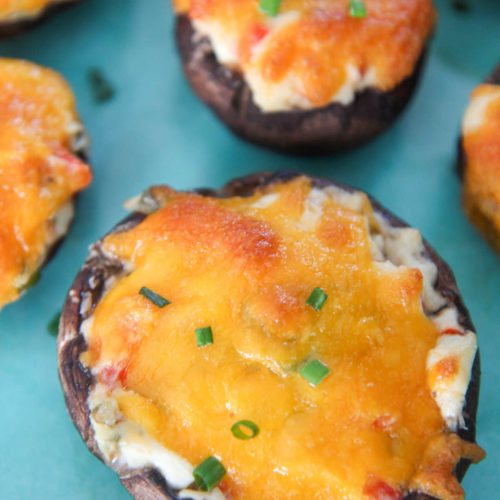 stuffed mushrooms with green chives on top of a blue plate