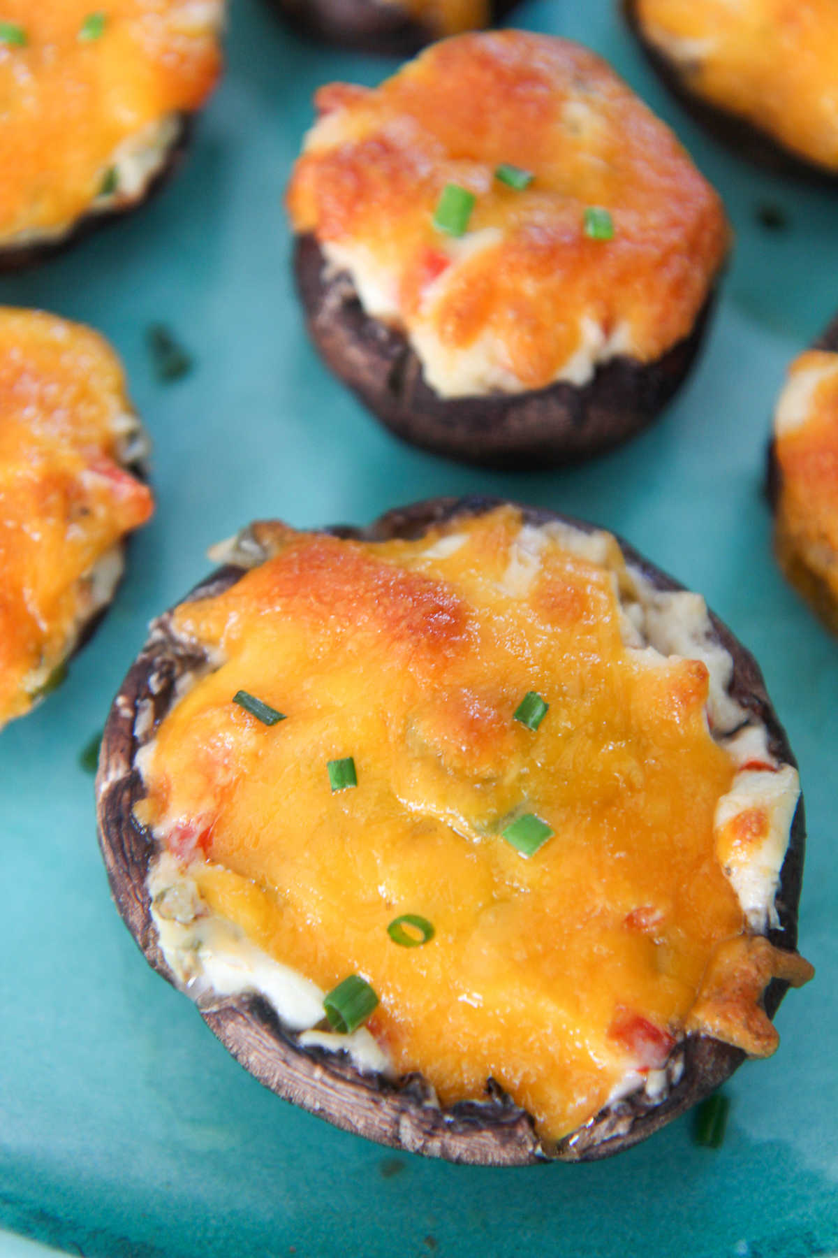 stuffed mushrooms with green chives on top of a blue plate