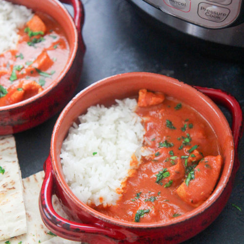 two small bowls with butter chicken and pita bread