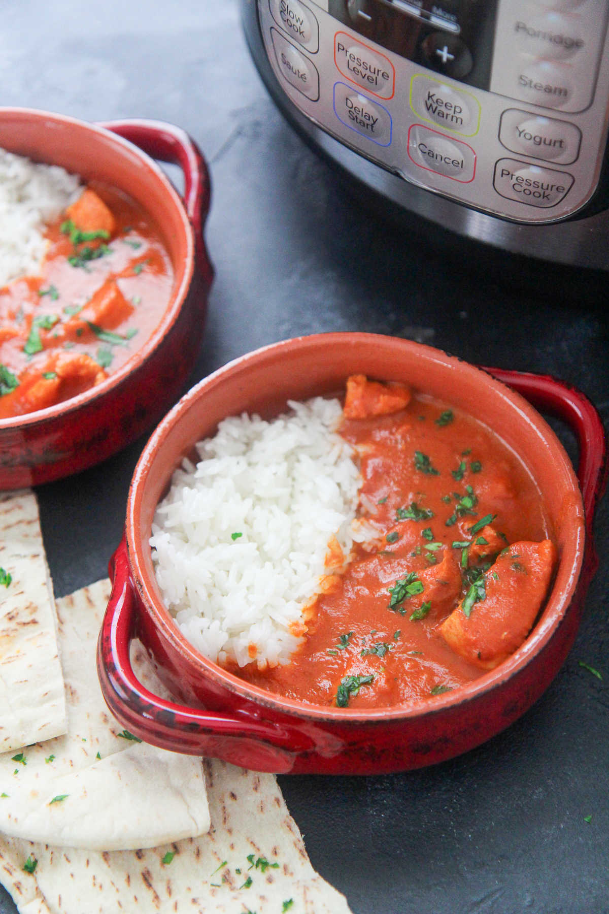 two small bowls with butter chicken and pita bread