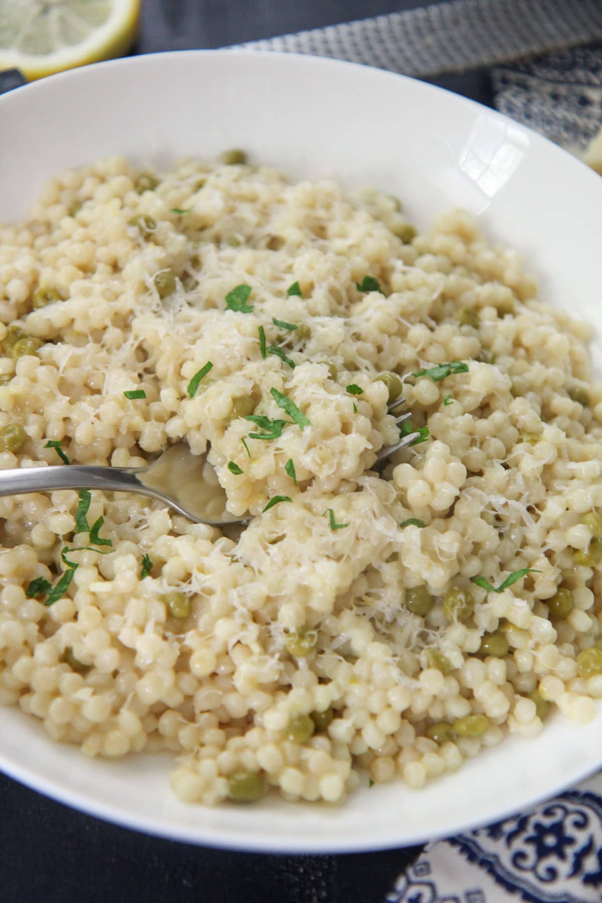 lemon pearl couscous in a white plate with a fork 