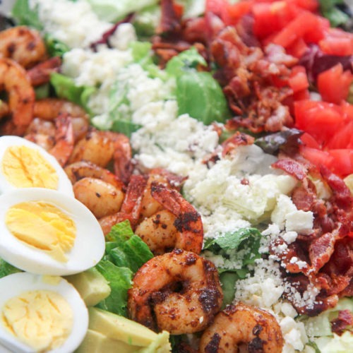 shrimp cobb salad with boiled eggs in a white plate