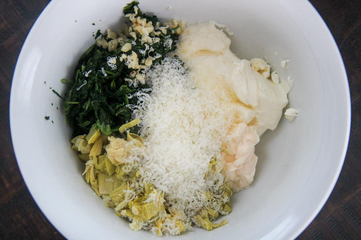 spinach, cheese, and artichokes in a white bowl 