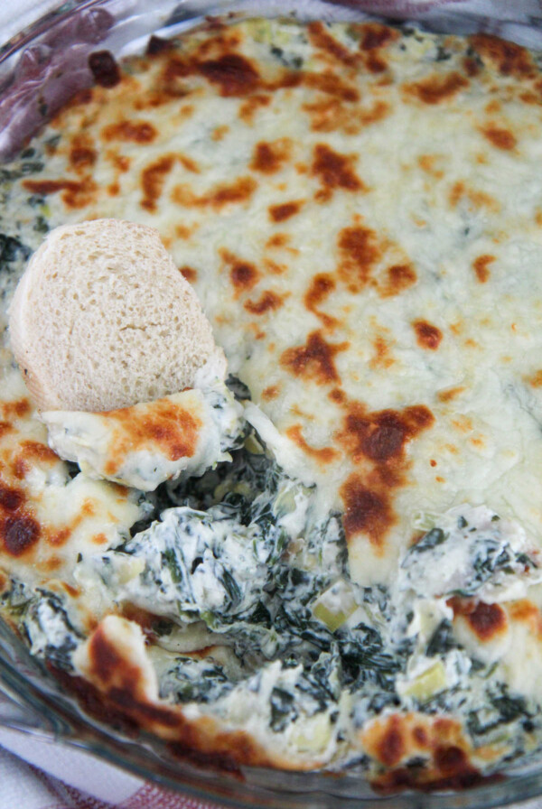 spinach and artichoke dip in a glass bowl with bread
