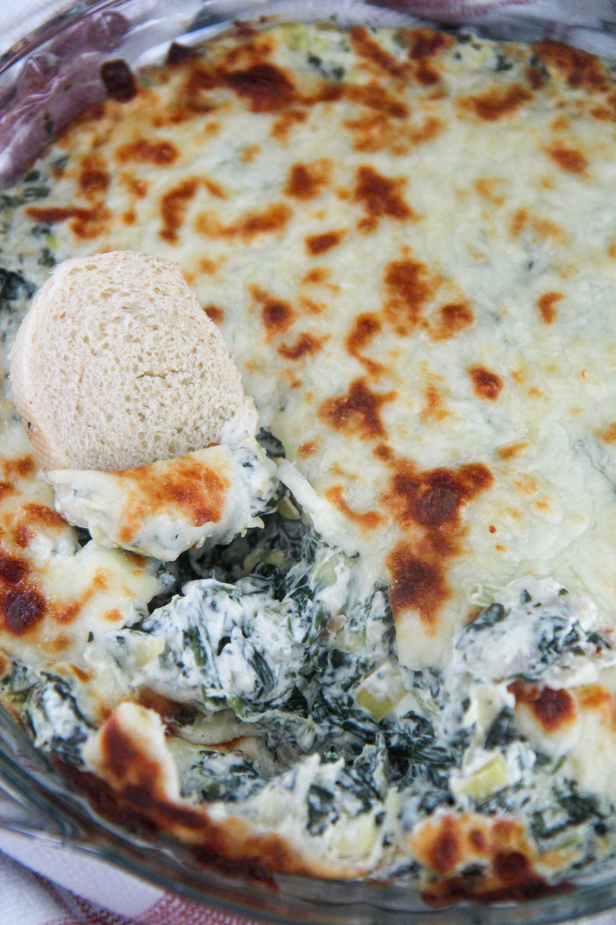 spinach and artichoke dip in a glass bowl with bread