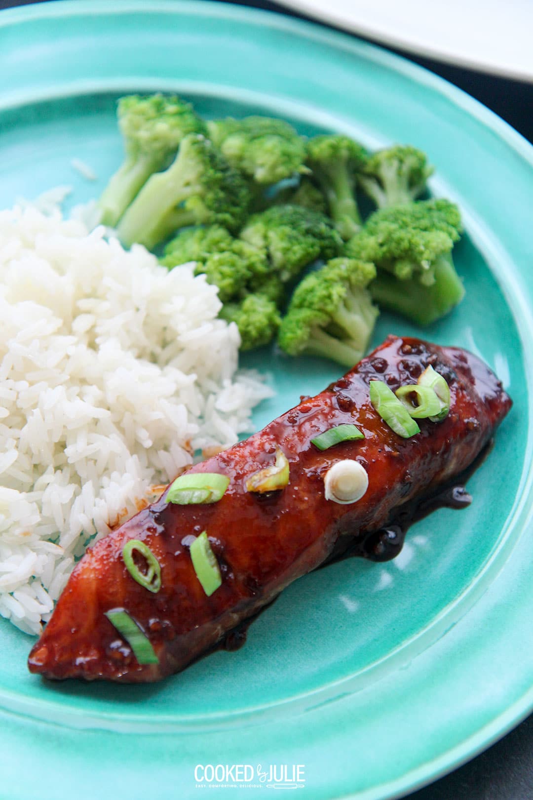 firecracker baked salmon with scallions and rice and broccoli on a blue plate 