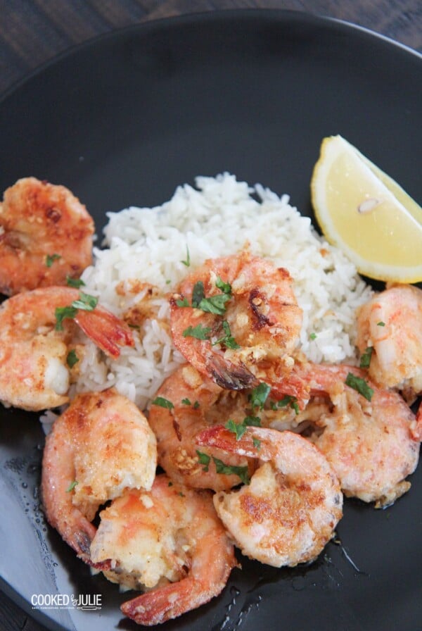 Hawaiian garlic shrimp, white rice, and lemon on a black plate