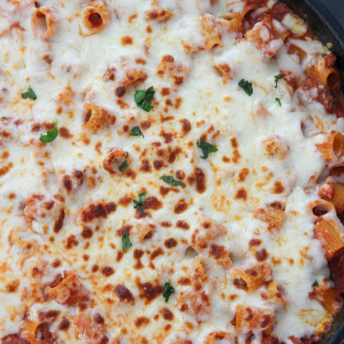 rigatoni with sauce and cheese in a black skillet