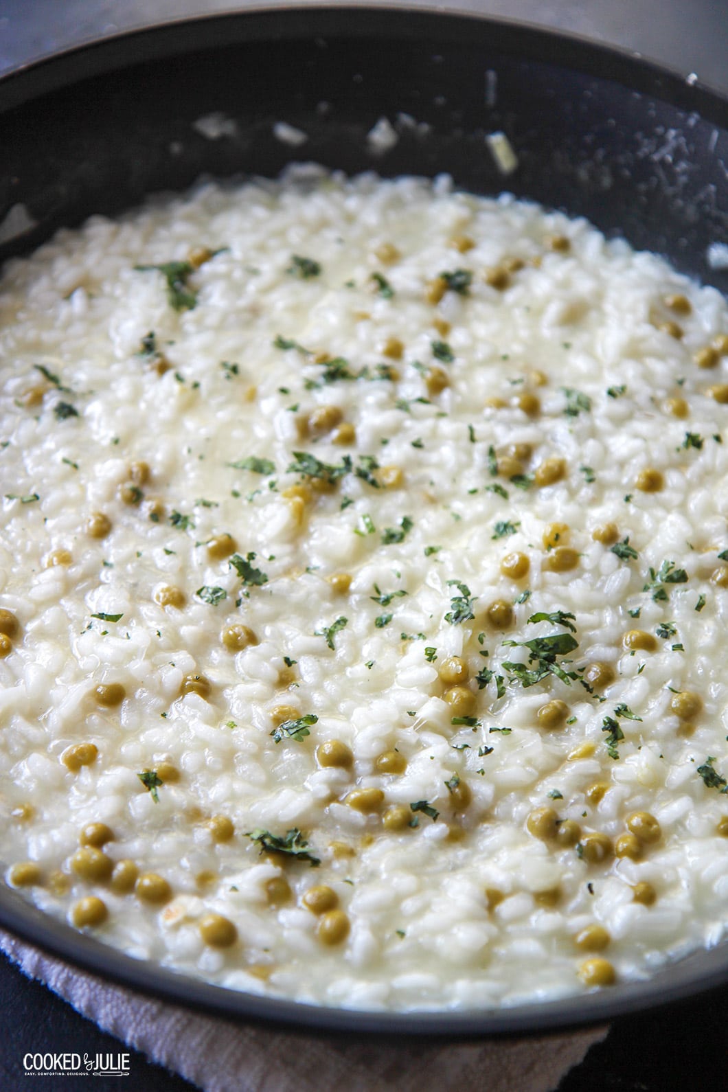 parmesan risotto with green peas in a black skillet