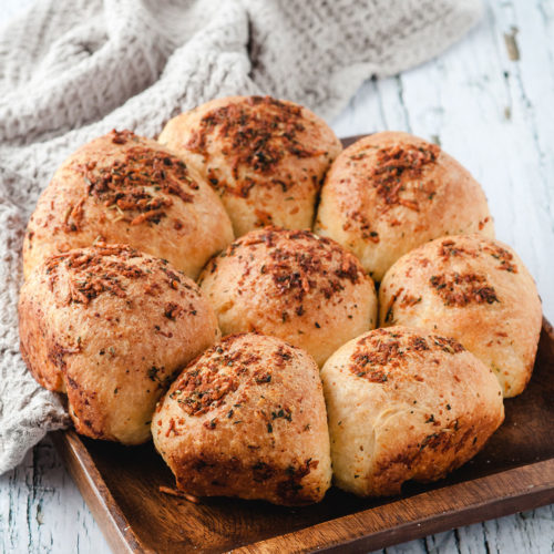 eight dinner rolls on a wooden board