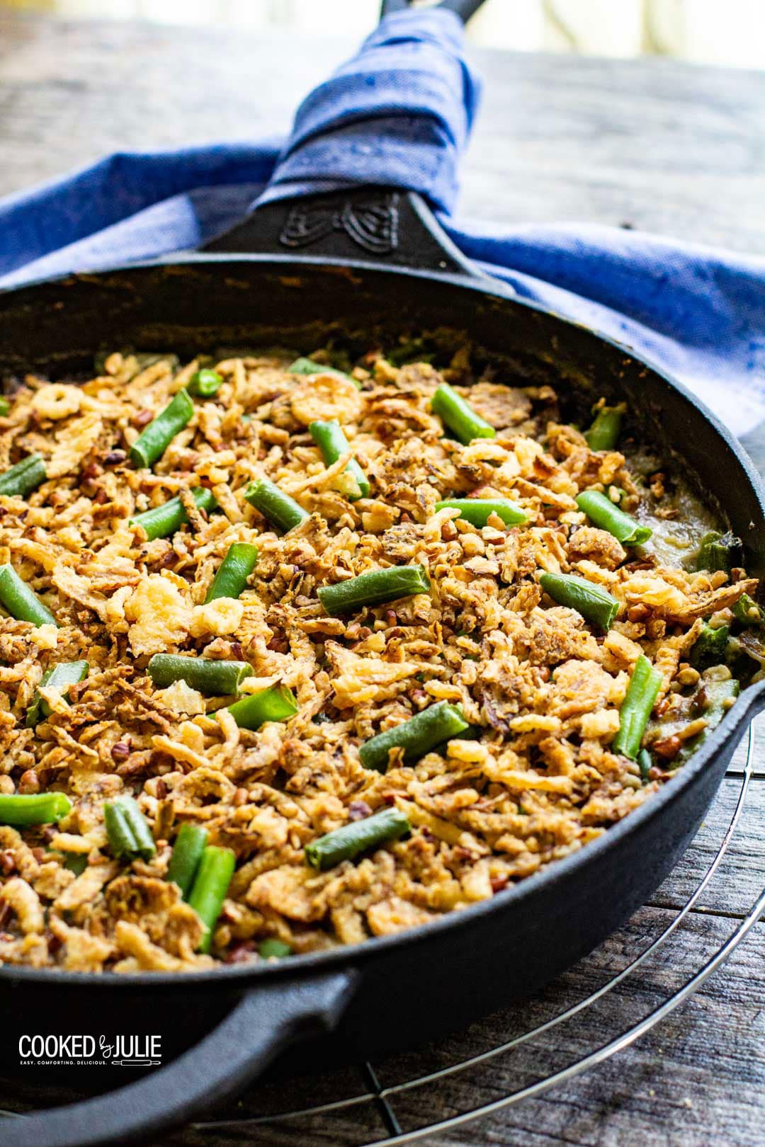 green bean casserole in an iron skillet with a blue towel