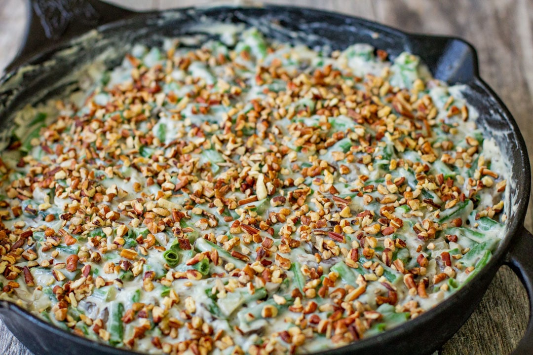 green bean casserole with pecans in a black dish 