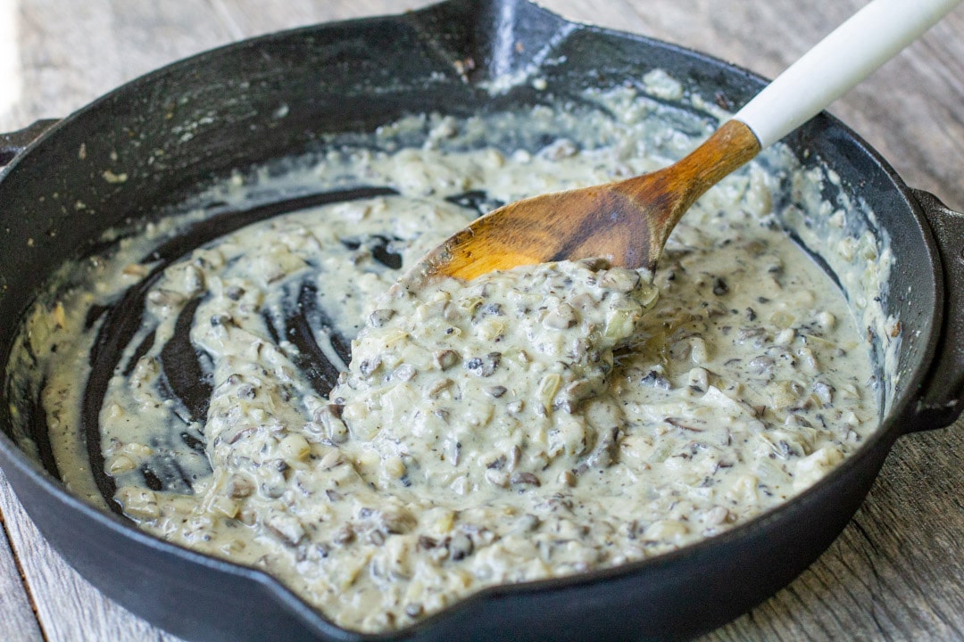 cream sauce in a black iron skillet with a wooden spoon