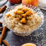 rice pudding and peaches in a glass bowl with peaches on the side