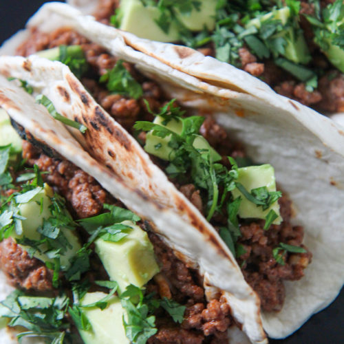 three Cajun beef tacos on a black plate