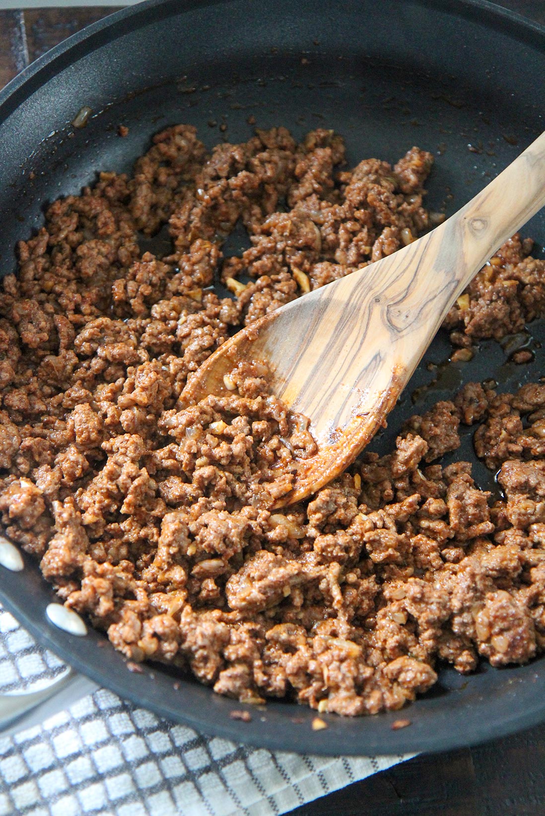 ground beef in a skillet with a wooden spoon 