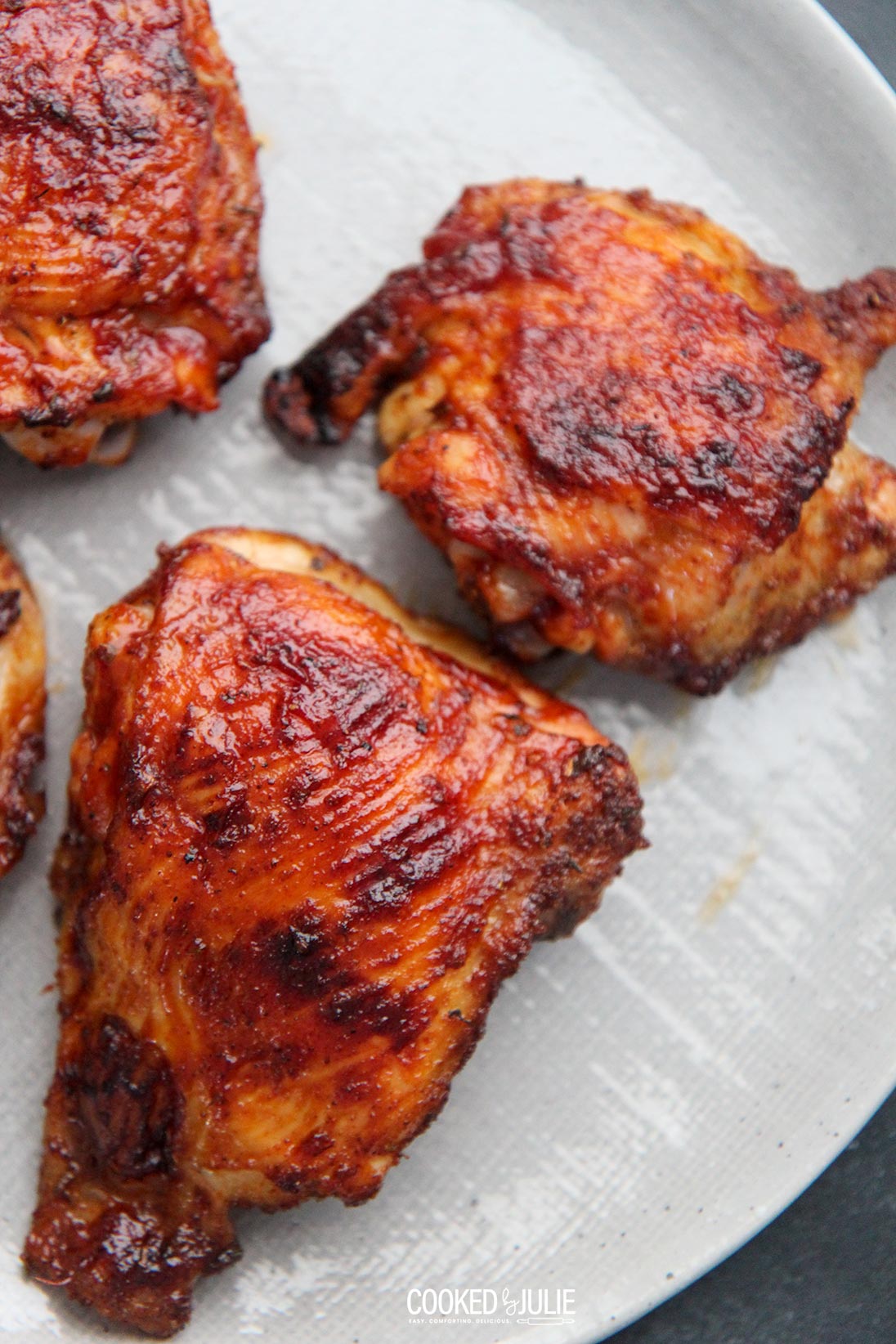 three bbq chicken thighs on a gray plate 