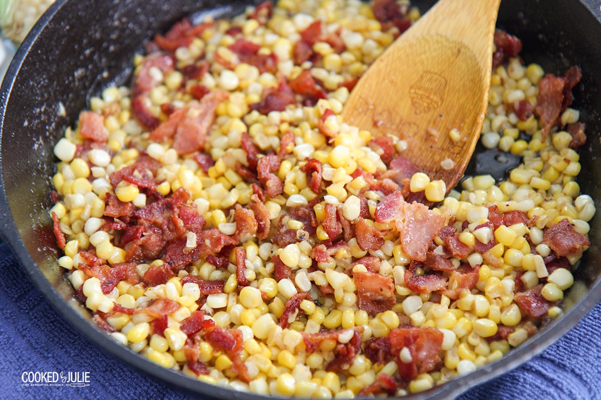corn and bacon in a skillet with a wooden spoon 