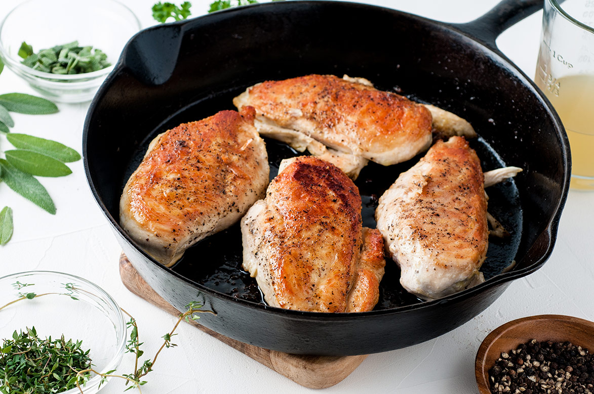 four cooked chicken breasts in an iron skillet