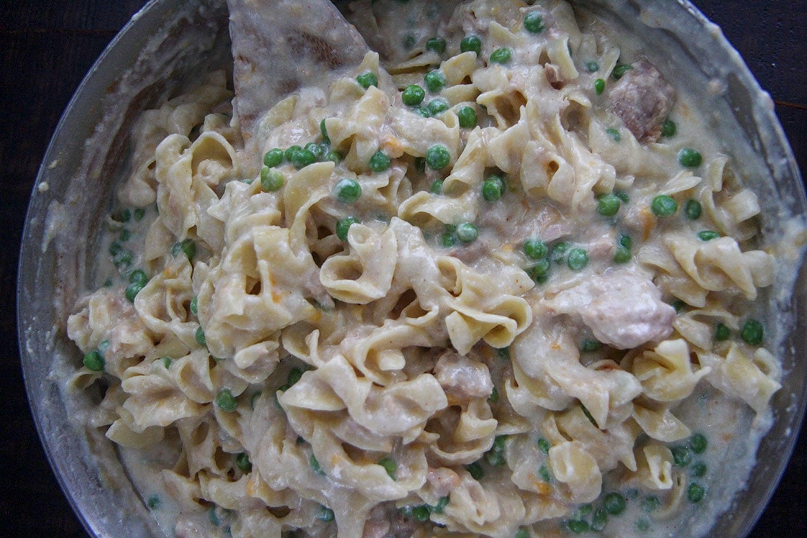 cream sauce, egg noodles, peas, and tuna in a skillet 