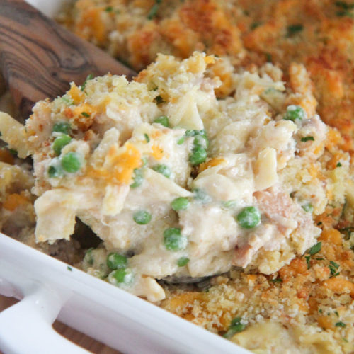 tuna noodles in a white baking dish with a wooden spoon