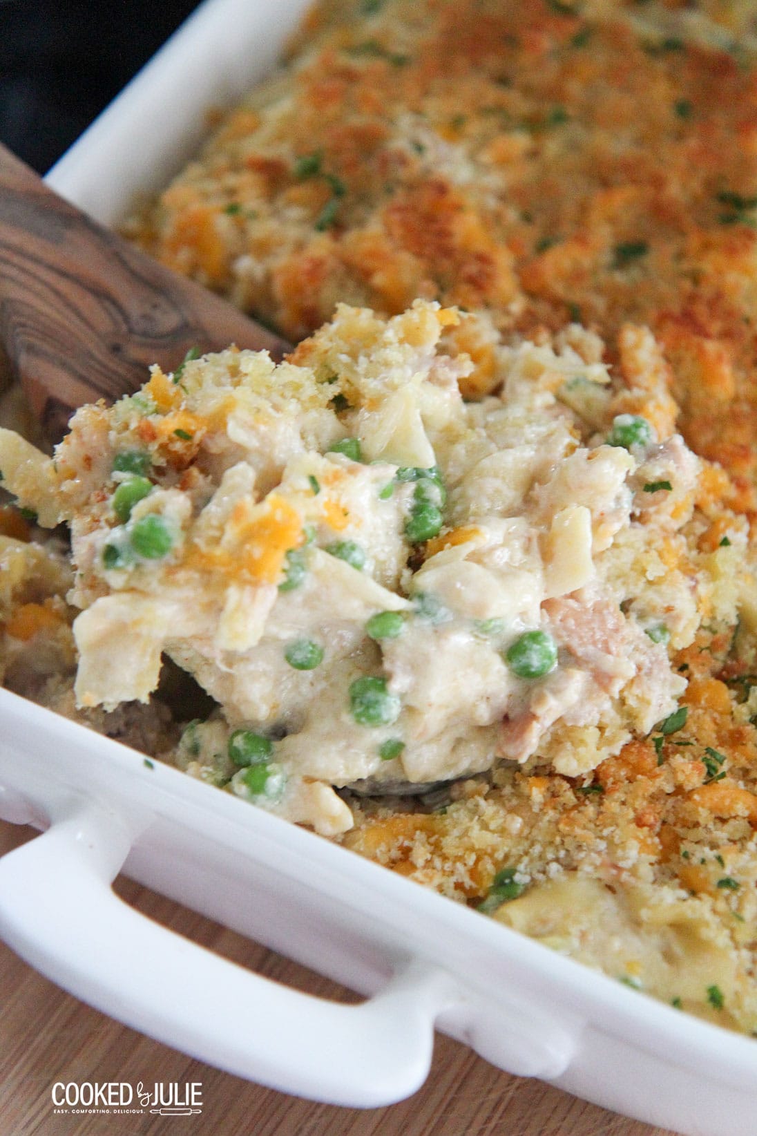 tuna noodles in a white baking dish with a wooden spoon