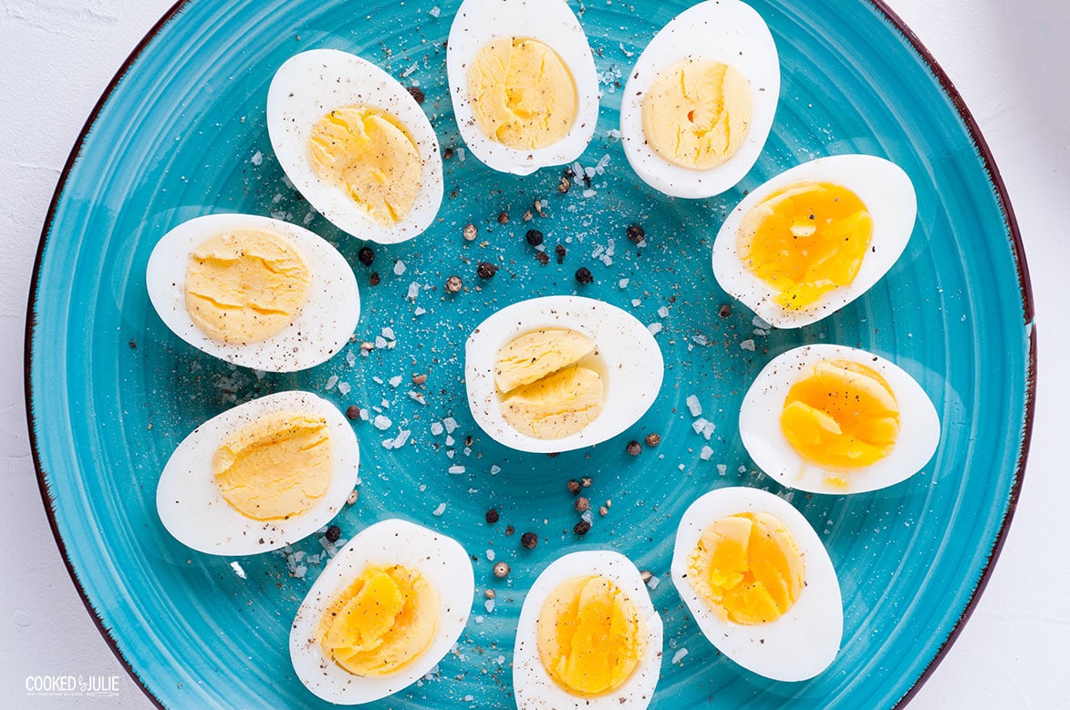 sliced soft and hard cooked eggs arranged in a flower patter and sprinkled with salt and pepper on a teal plate