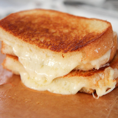 two grilled cheese sandwiches on a wooden board