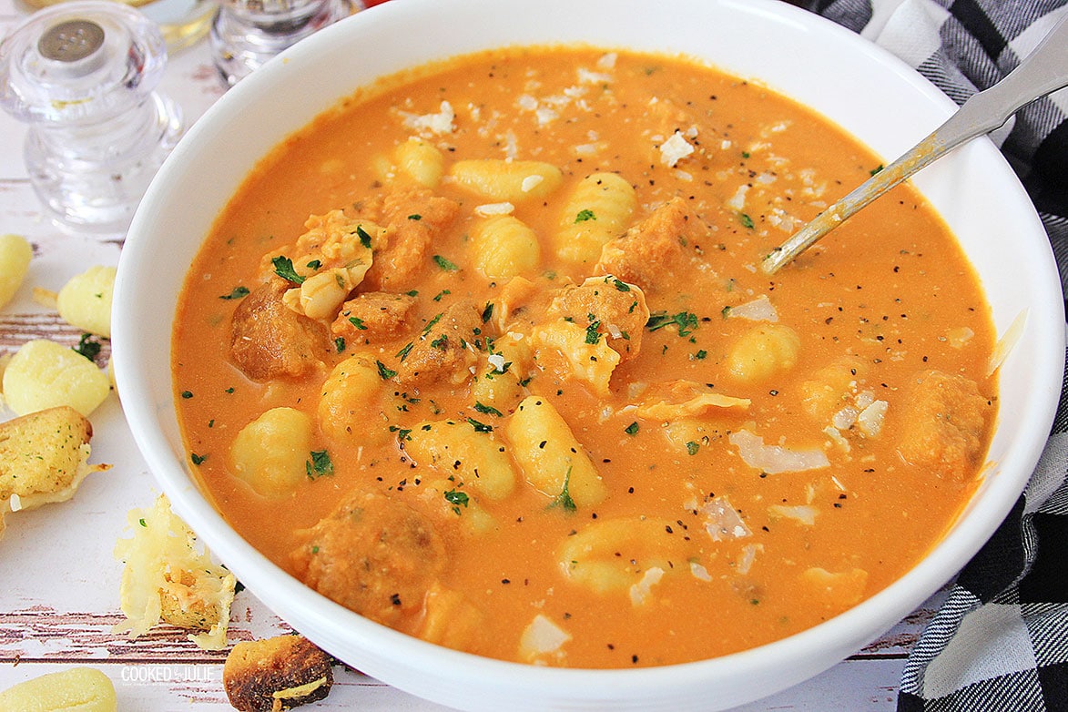 tomato gnocchi soup in a white bowl with croutons on the side 