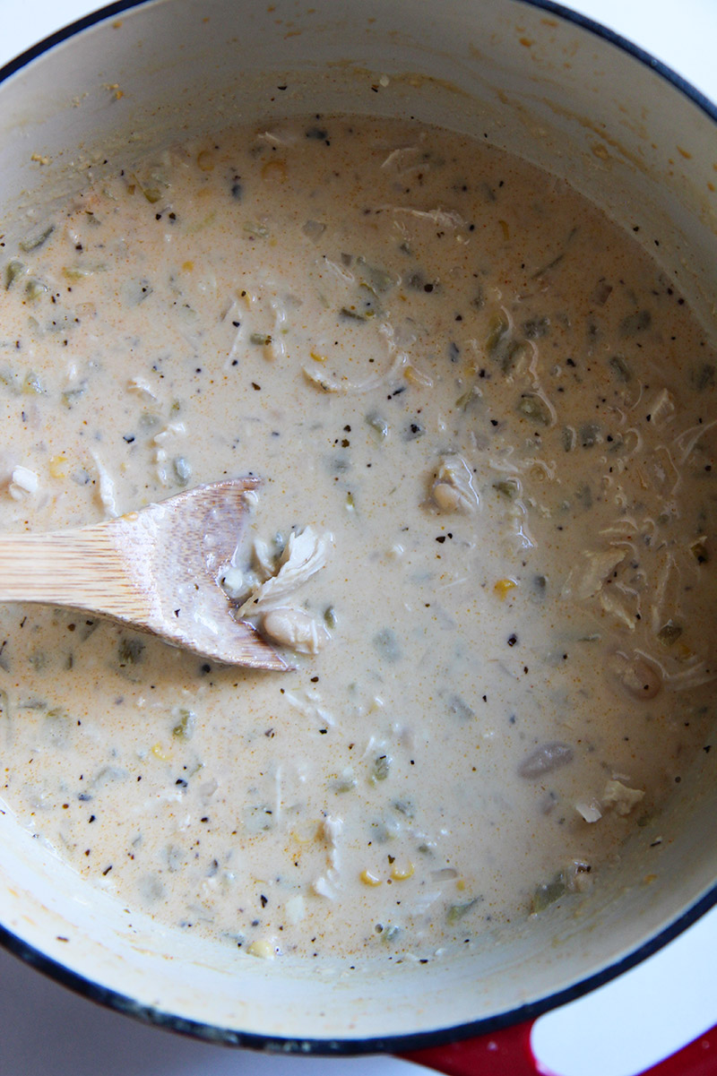 creamy white chicken chili in a dutch oven with a wooden spoon