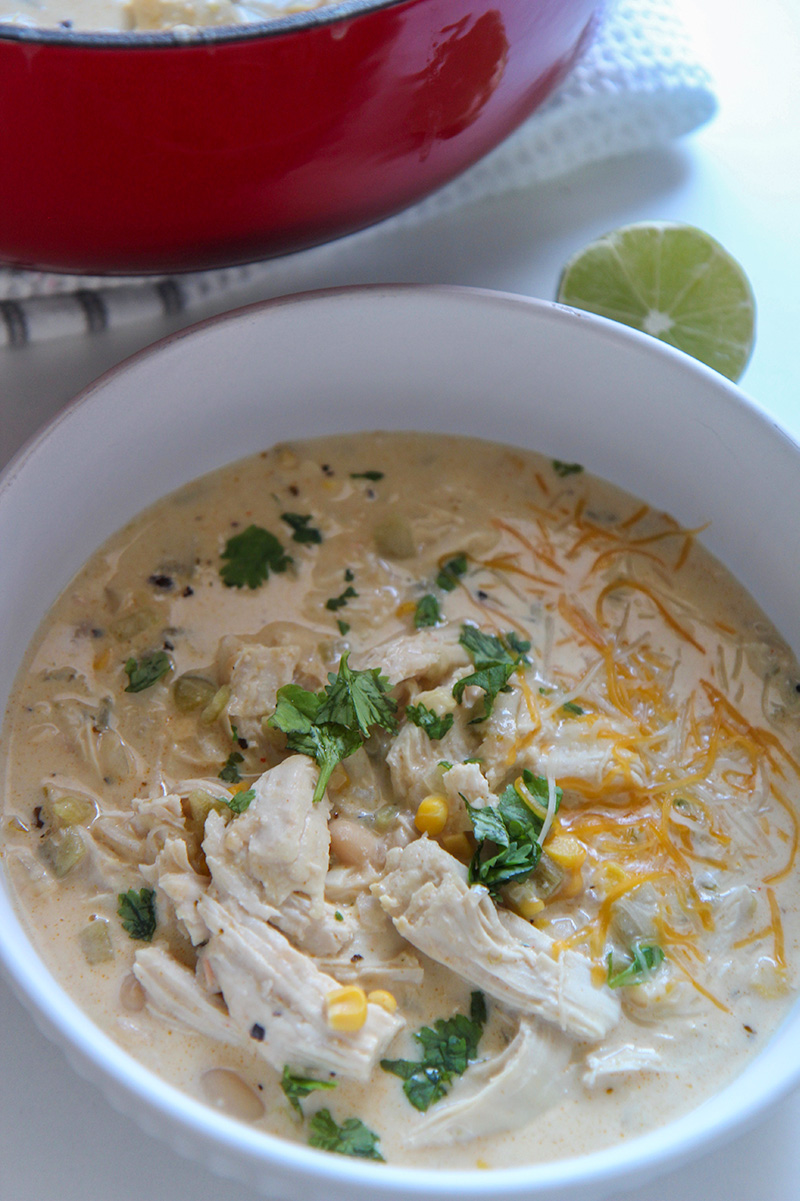white chicken chili in a white bowl with lime on the side