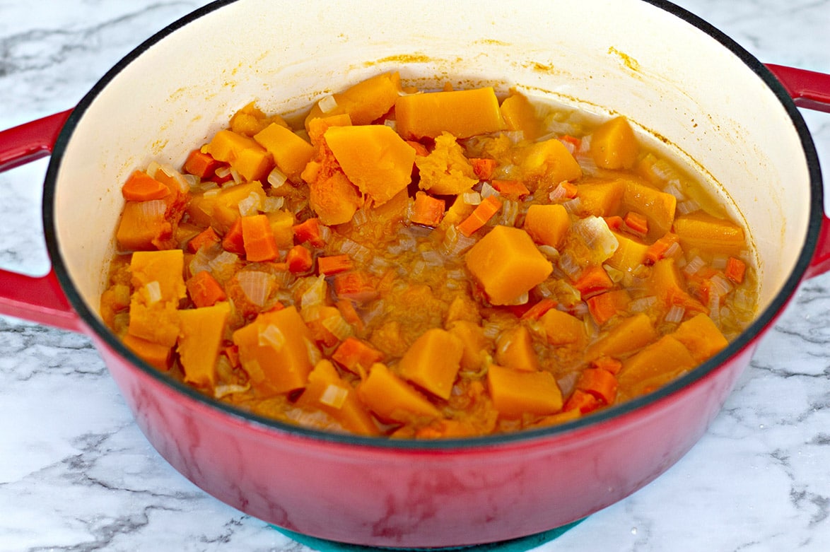 vegetables and chicken stock in a red dutch oven 