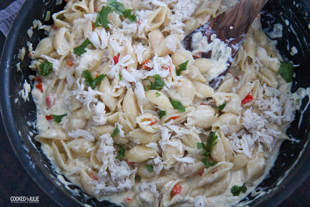 pasta shells with crab meat in a black skillet and a spoon. 