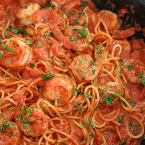 creamy spicy shrimp spaghetti with parsley in a black skillet