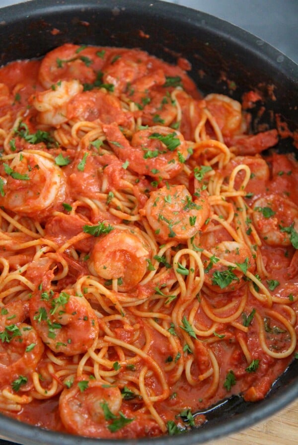 creamy spicy shrimp spaghetti with parsley in a black skillet