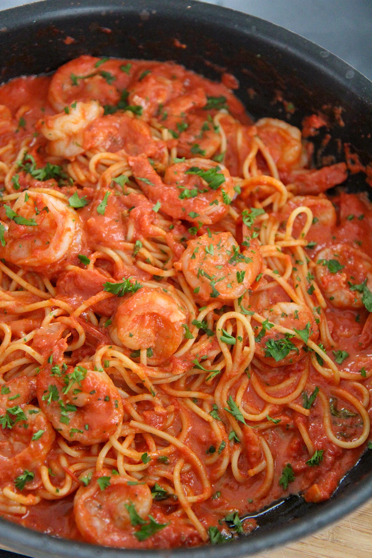 creamy spicy shrimp spaghetti with parsley in a black skillet 