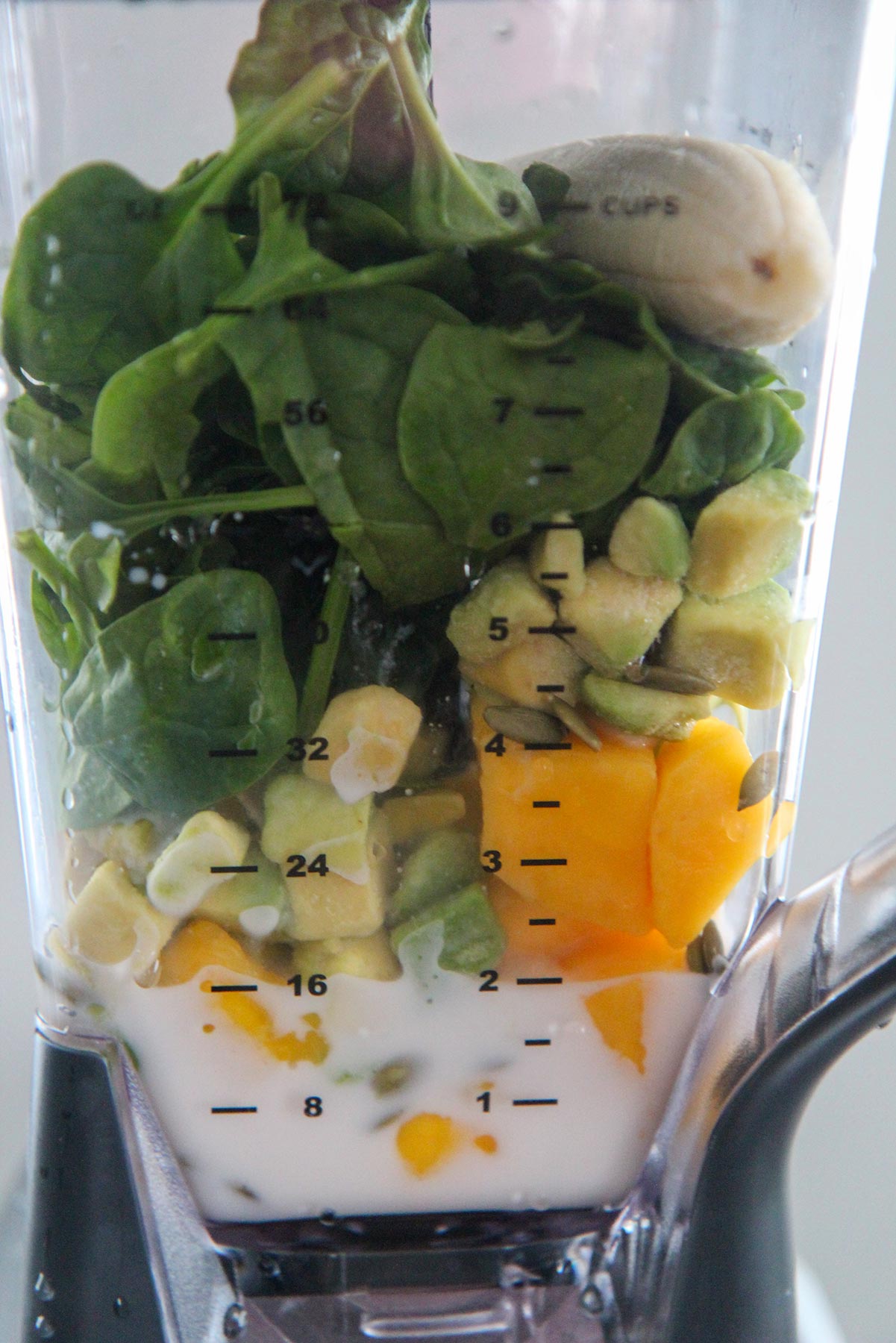 spinach, mango, banana, avocado, and almond milk in a blender