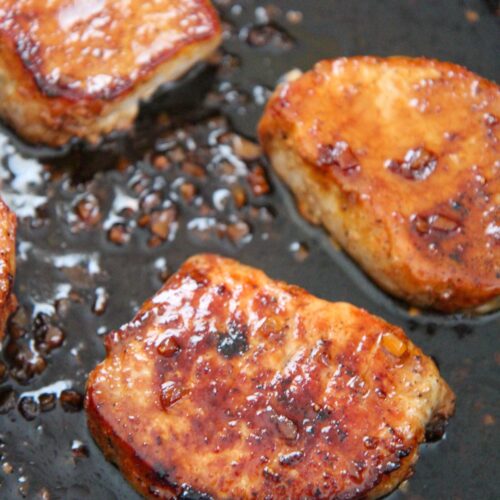 three honey garlic pork chops in a black skillet