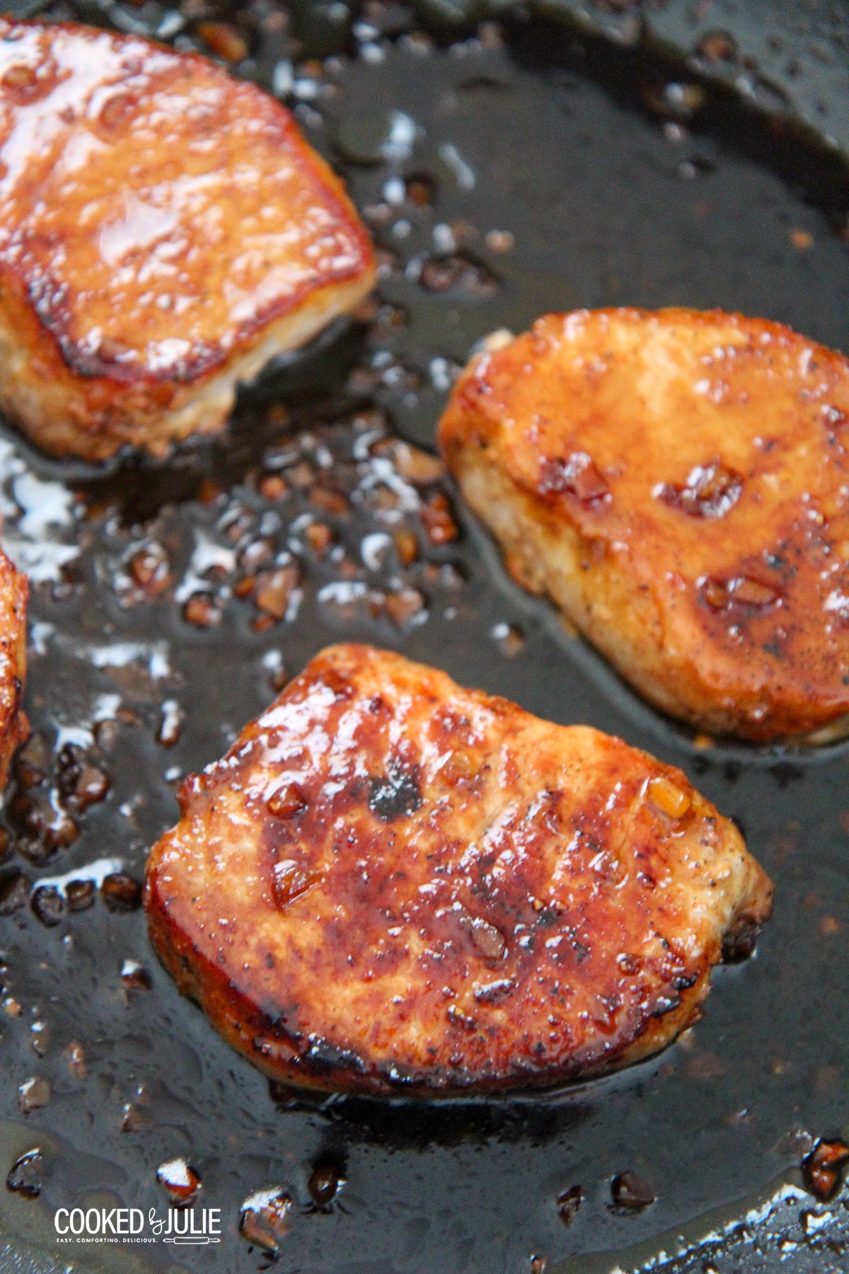 three honey garlic pork chops in a black skillet 