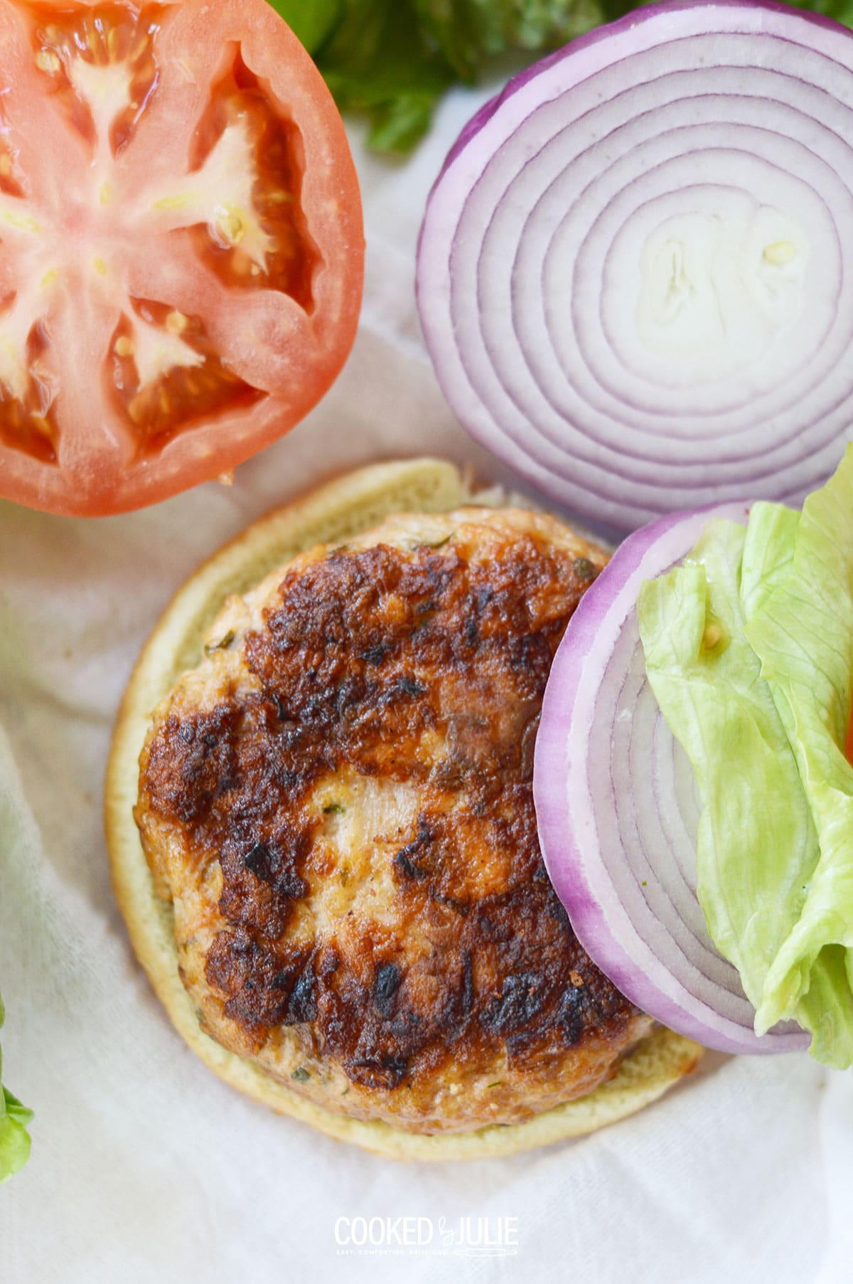 salmon burger with lettuce, tomato, and onions