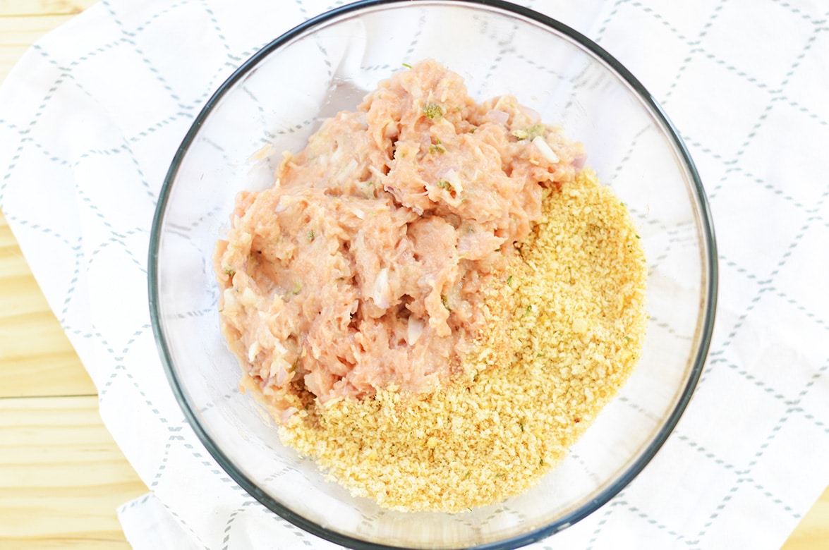 meat mixture and breadcrumbs in a clear bowl.