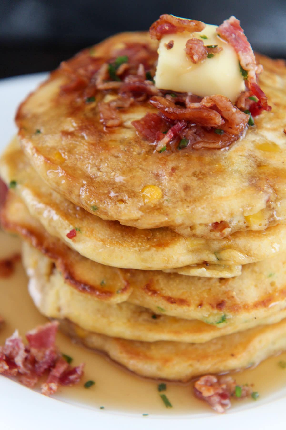 pancakes with a slice of butter and crispy bacon on top up close. 