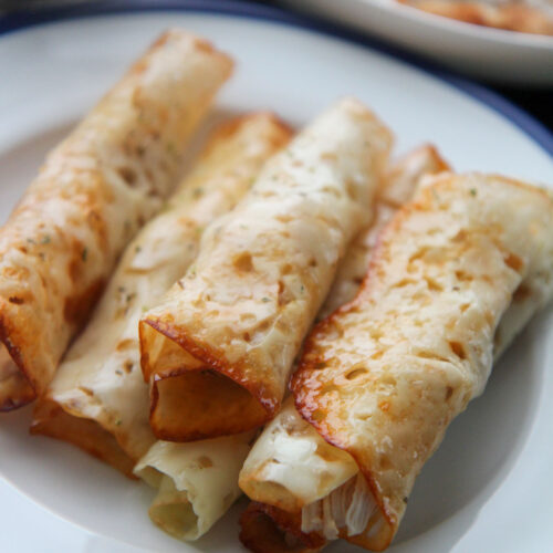 six keto cajun chicken taquitos on a white and blue plate