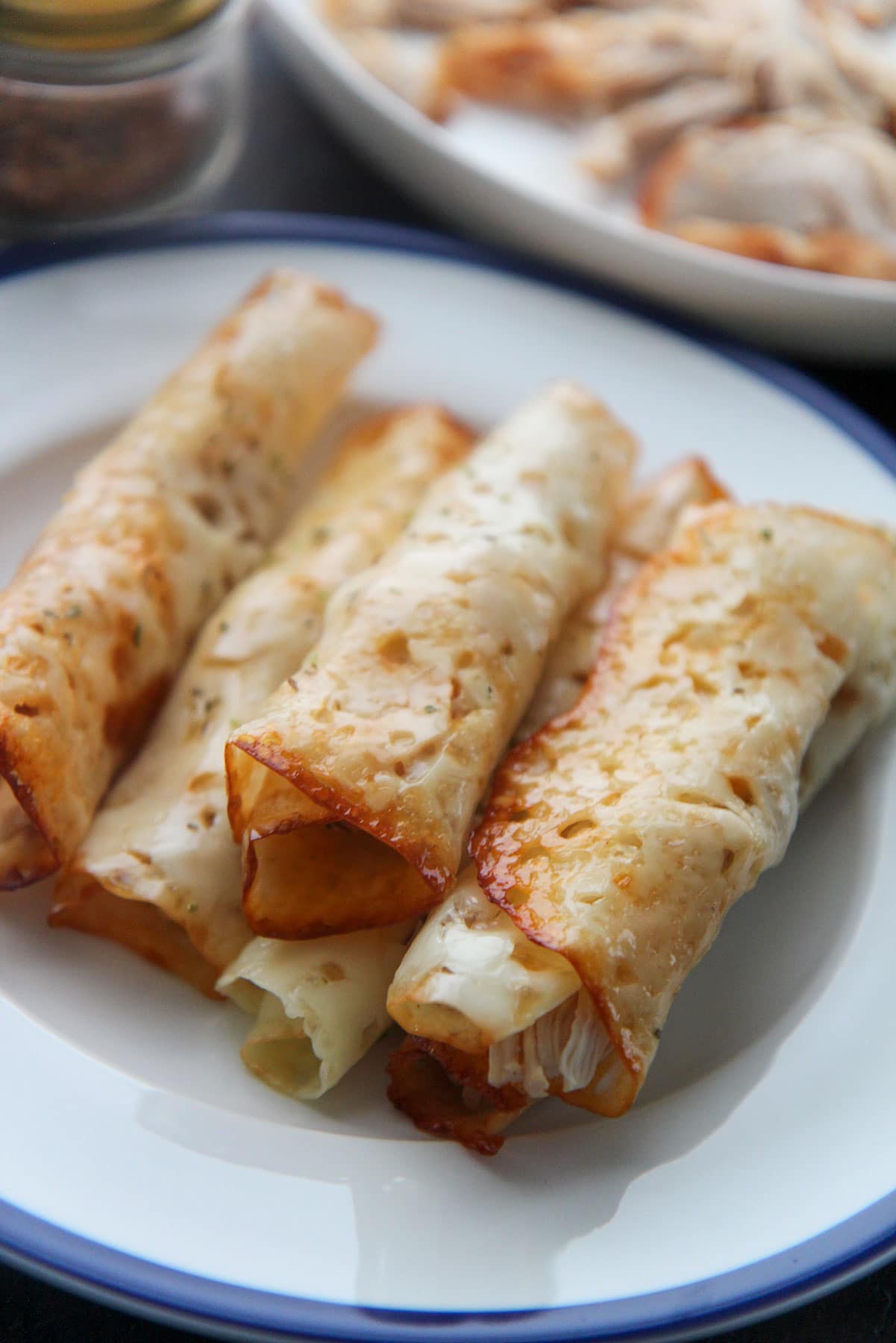 six keto cajun chicken taquitos on a white and blue plate 