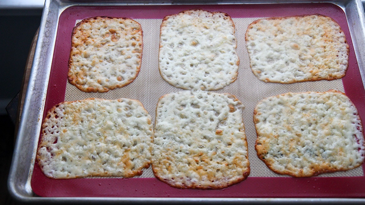 six mozzarella cheese slices melted on a baking sheet 